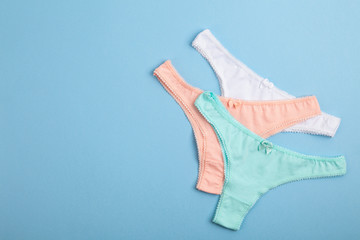 Female pastel cotton set panties and cotton flower on blue background. Beautiful lingerie. Top view, flat lay. Women's natural underwear. 