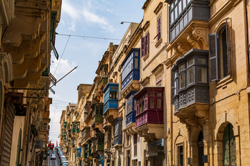 Residential house facade with traditional Maltese multicolored enclosed wooden balconies in Valletta, Malta, in summer day. Authentic Maltese urban scene.