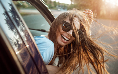 Passenger girl's magnificent hair fluttering as she leans out of the car window