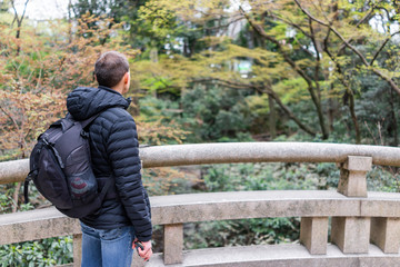 Tokyo, Japan Meiji shrine during spring with tourist person man standing looking at view from stone bridge in park