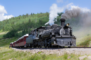 Vintage Steam Train Billowing Smoke as it Moves Through the Mountains.