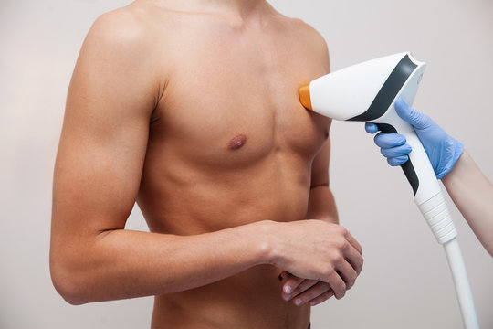 Muscular athlete man with smooth clear skin. Epilation and depilation of hair in beauty salon. Male laser hair removal concept. Beautician using modern apparatus for procedures. Skin and Beauty Care