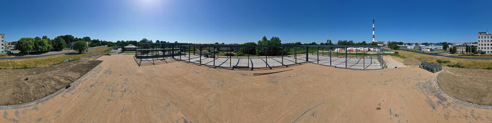 Fototapeta na wymiar Aerial drone wide perspective panoramic view on steel construction frame, on building site, concrete floor with metal pipe supports and brick paving