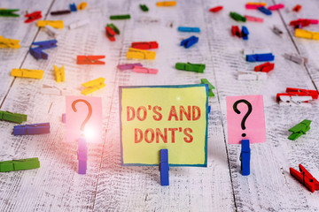 Handwriting text Do S And Dont S. Conceptual photo Rules or customs concerning some activity or actions Scribbled and crumbling sheet with paper clips placed on the wooden table