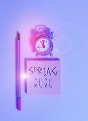 Text sign showing Spring 2020. Business photo text time of year where flowers rise following winter season Metal vintage alarm clock wakeup blank notepad marker colored background