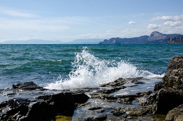 Traveling to the sea, a wave rolls over stones.
