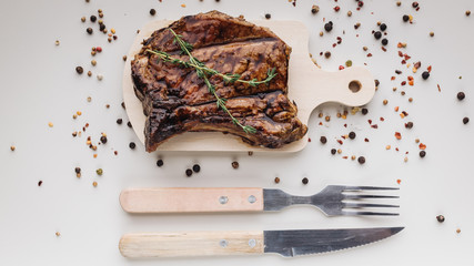 Appetizing medium rar grilled t-bone steak on a wooden cutting board on a light background with...