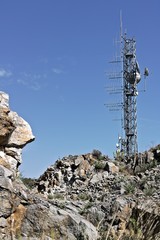 Trellis with numerous transmitting antennas installed on a rocky mountain.