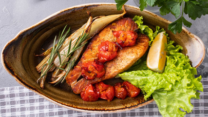 Baked salmon with cherry tomatoes and celery on a plate. Top view