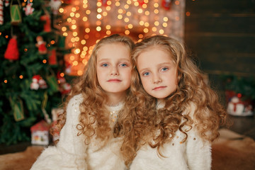 Merry Christmas and happy New Year. Happy little sisters on the background of Christmas decorations and gifts