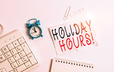 Writing note showing Holiday Hours. Business concept for Overtime work on for employees under flexible work schedules Blank paper with copy space on the table with clock and pc keyboard