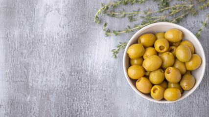 Green olives on grey background with copy space. Top view