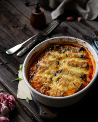 baked eggplant rolls with tomato sauce, melted cheese in white ceramic oval baking pan