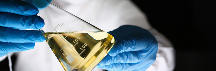 Male chemist look at microscope hold test tube