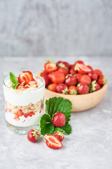 Strawberry granola or smoothie in glass and fresh berries in a wooden bowl. Healthy breakfast