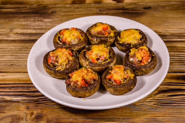 Baked champignons stuffed with minced meat and cheese in plate on a wooden table
