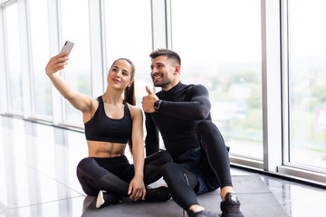 Young fitness couple taking a sefie in a gym