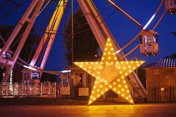 Foto op Plexiglas Illuminated glowing star in amusement park at the night city © Lazy_Bear