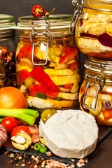 Pickled Cheese with Red onion. Homemade preparation of pickled cheese. Pickled food. Jar with Camembert cheese marinated in oil on black wooden table.