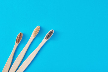 three wooden bamboo toothbrushes on a blue background, top view.  Dental care concept
