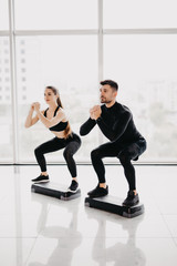 Obraz premium Fit couple working out make squats together at gym