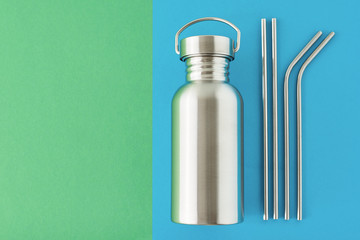Zero waste eco friendly concept. Reusable plastic free items on a colorful blue and green background. Top view of aluminun bottle and metal tubes