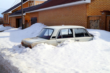 The car is covered in snow after heavy snowfall.
