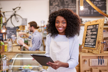 Smiling African America barista using a tablet in her cafe