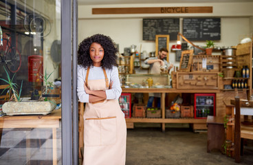 Friendly African American barista standing at a cafe door