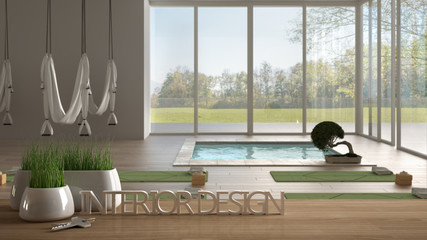 Wooden table, desk or shelf with potted grass plant, house keys and 3D letters making the words interior design, over empty yoga studio, meditation room, project concept background