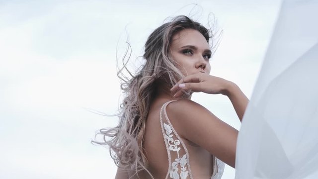 Attractive girl in a beautiful white dress in nature, the wind develops hair