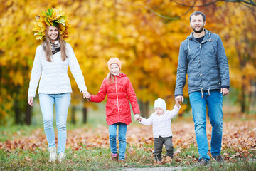 Fototapeta premium Portrait of happy young family with baby girl in autumn park