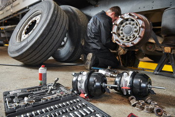 Truck repair service. Mechanic works with brakes in truck workshop - 297154677