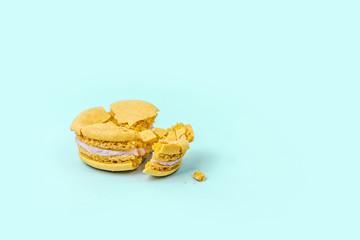 Crushed yellow macaroon on pastel blue background with copy space.