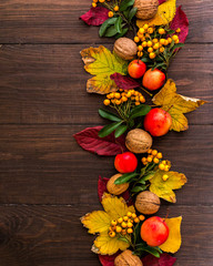 Liście, orzechy, jarzębina i dary jesieni na drewnianym tle, miejsce na napis 