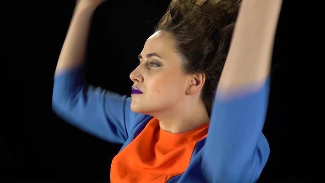 Close up of girl in bright dress, unusual makeup and crazy hairstyle makes hand gestures