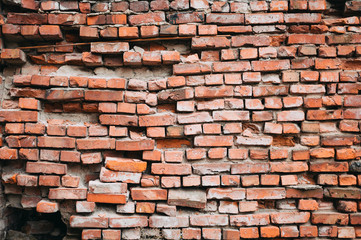 Fototapeta premium A crumbling red brick wall. Vintage background