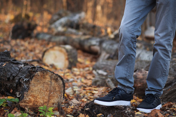 Men's feet in stylish black sneakers in autumn Park or forest. Seasonal shoes. Copy space