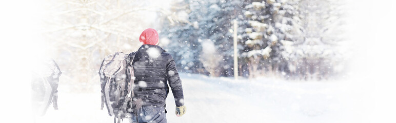 A man travels with a backpack. Winter hike in the forest. Tourist on a walk in the winter in the park.