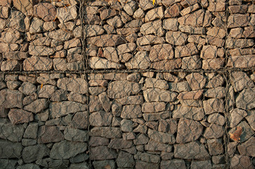 Stone wall. Stones behind the wire