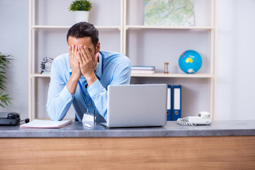 Young male travel agent working in the office