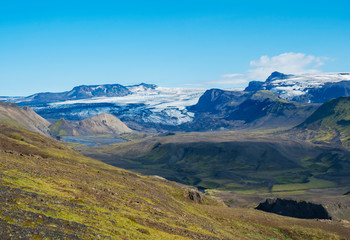 Fototapeta na wymiar Icelandic landscape with eyjafjallajokull glacier tongue, Markarfljot river and green hills. Fjallabak Nature Reserve, Iceland. Summer blue sky