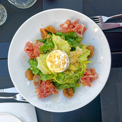 gourmet green salad plate served with proschiutto and ricotta white cheese, top view
