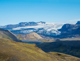 Icelandic landscape with eyjafjallajokull glacier tongue, Markarfljot river and green hills. Fjallabak Nature Reserve, Iceland. Summer blue sky