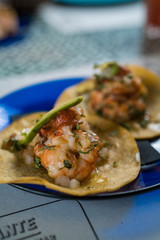 Real Mexican Tacos on a plate. Real Mexican Tacos on a plate. Shrimp tacos with homemade salsa, limes and parsley on wooden board over dark background. Top view. Mexican cuisine