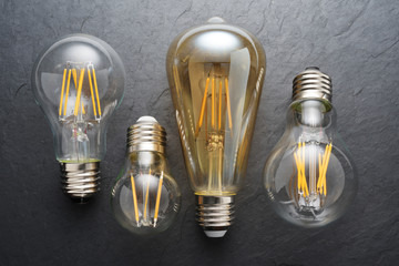 Transparent LED filament light bulbs on black background. - obrazy, fototapety, plakaty