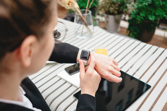 Top view of businesswoman using smartphone and smartwatch for conversation with customers digital social media project. Business lady sitting on veranda in coffee shop and using modern gadgets