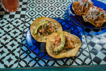 Real Mexican Tacos on a plate. Shrimp tacos with homemade salsa, limes and parsley on wooden board over dark background. Top view. Mexican cuisine