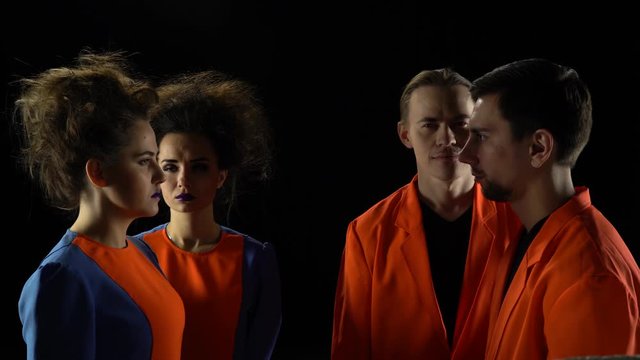 Two men and two women in bright clothes stand with their eyes closed and slowly open them. Crazy people