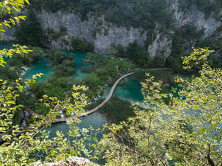 Croatia, august 2019: Tourists on the wooden park pathways enjoying the view of emerald lakes, cascades and crystal clear water, Plitvice Lakes National Park
